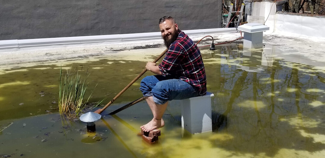 Man eliminating stagnant water on flat roof