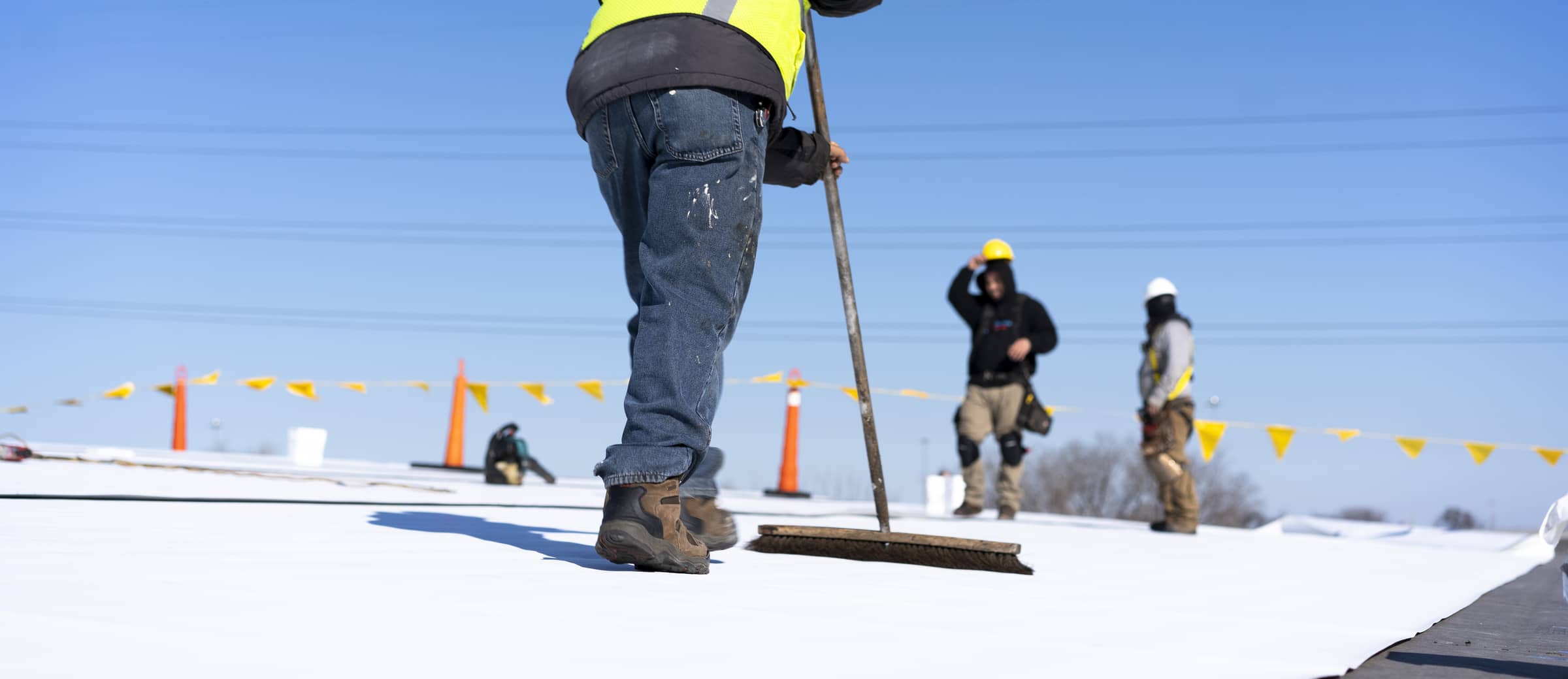 Un couvreur nettoie la membrane TPO avant son installation