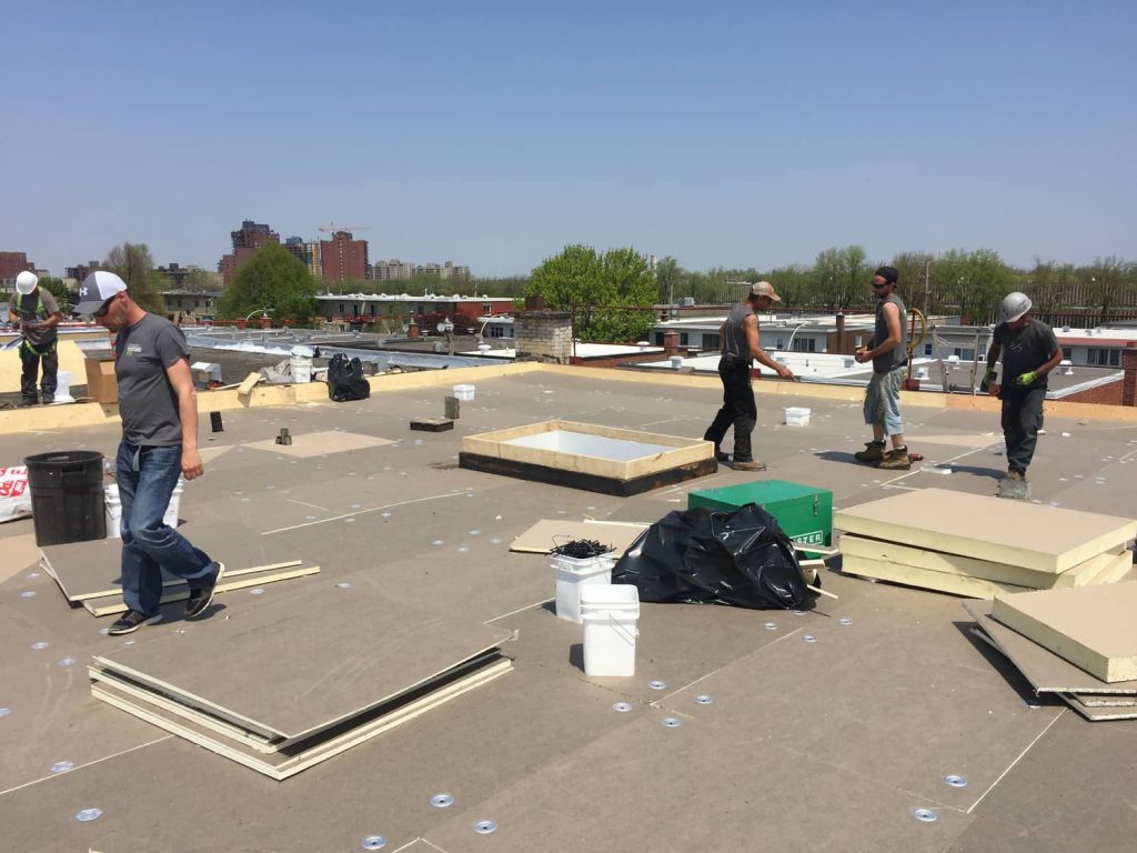 Les couvreurs de toit plat installent les panneaux de support qui accueilleront la membrane TPO