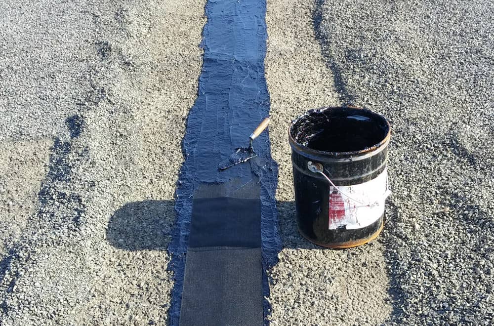 Réparation d'une jointure avec du feutre et de l'asphalte sur un toit plat en asphalte et gravier
