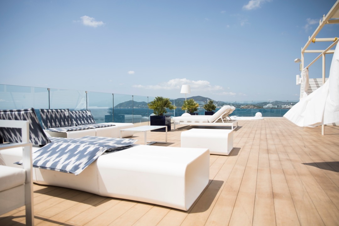 A flat roof terrace with white lounge chairs on a sunny day