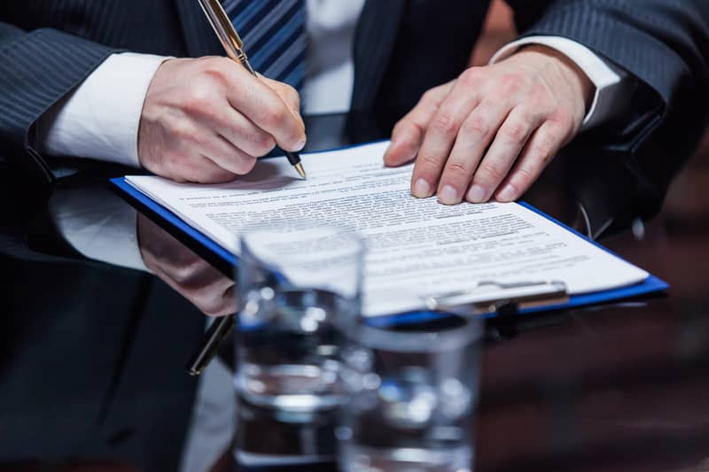 Un avocat des affaires signe un contrat papier