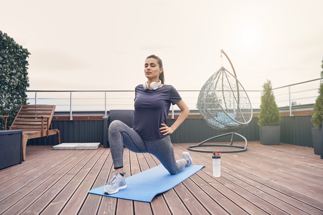Jeune femme pratiquant un activité physique de yoga sur un toit-terrasse