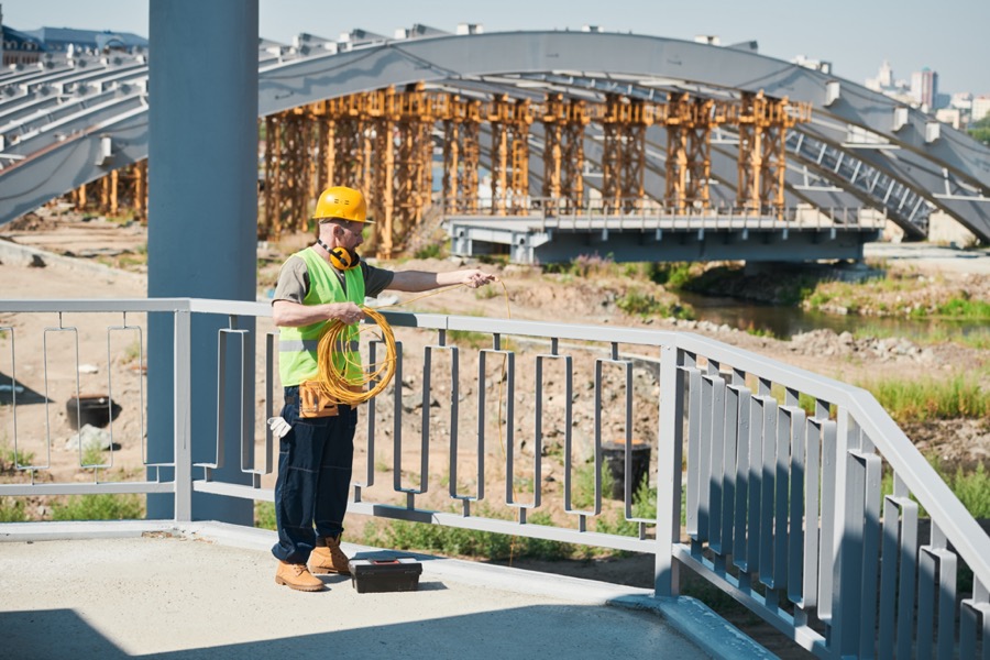 Construction worker at the edge of a guardrail on a building floor.