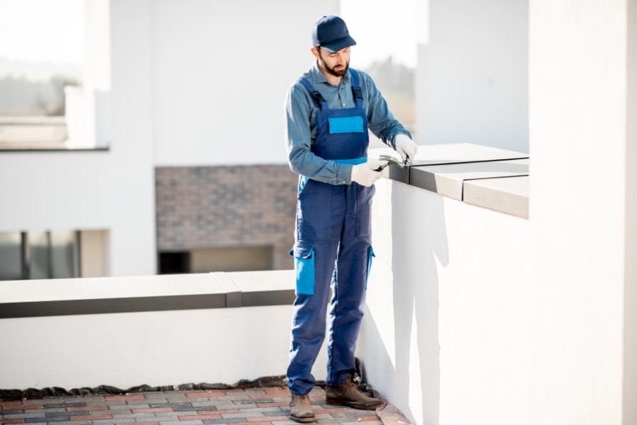 Builder installing a cover on the roof parapet.