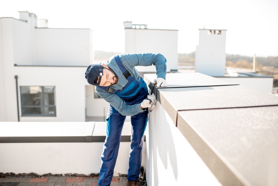 Builder adjusting a cover on a roof parapet.