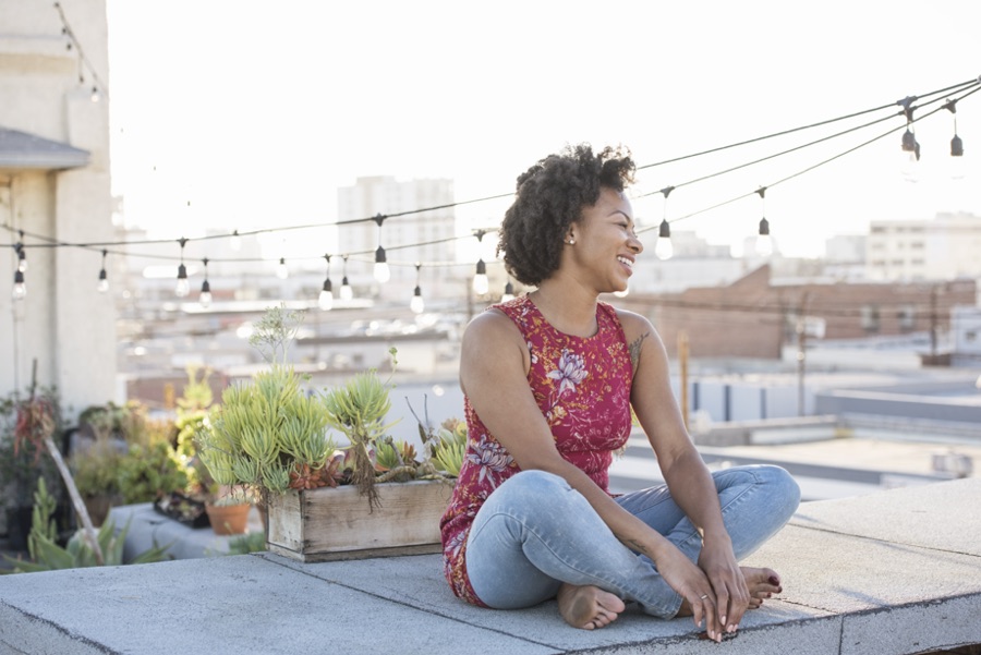 Young woman sitting on rooftop terrace, enjoying the sun.