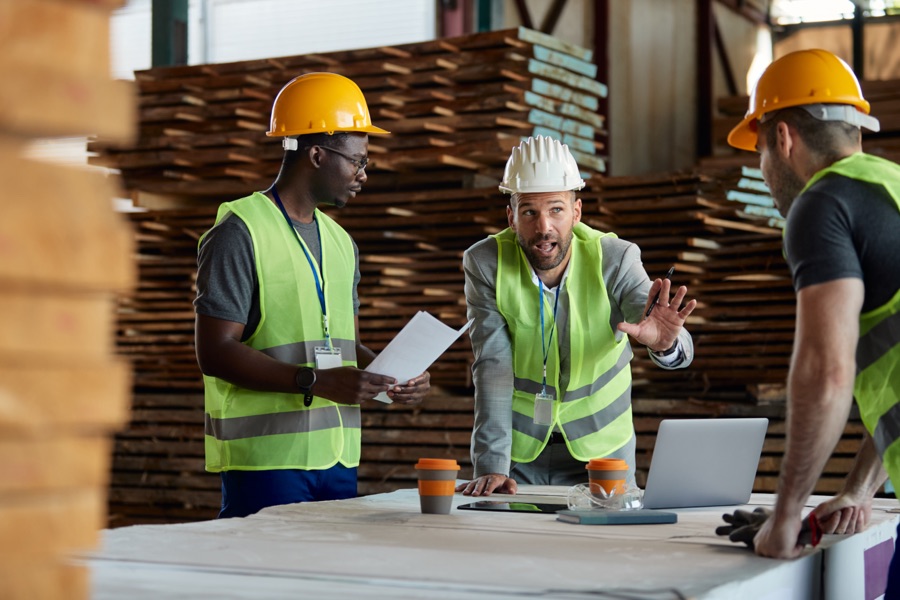 Warehouse inspector communicating with workers during a meeting at lumber compartment.