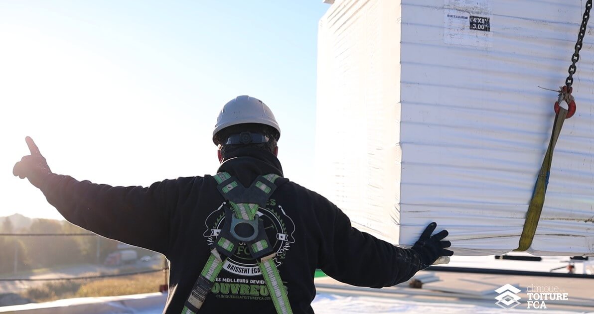 Worker guiding the arrival of insulation on a commercial roof.