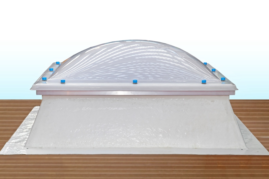 Gros plan d’un puits de lumière bombé pour toit plat, montrant la structure en acrylique et les fixations étanches.