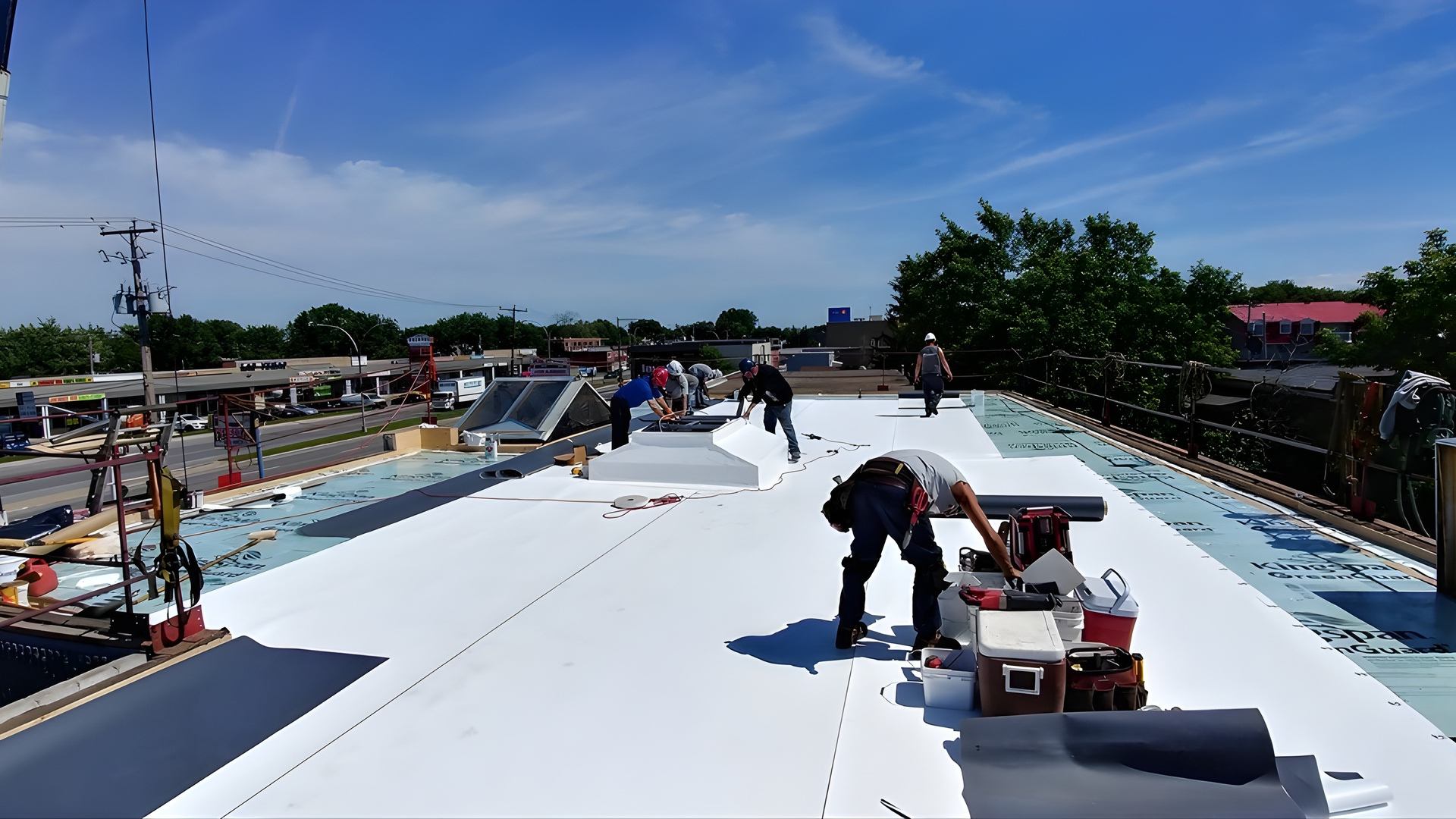 Équipe de couvreurs installant une membrane TPO blanche sur un toit plat commercial à Montréal.